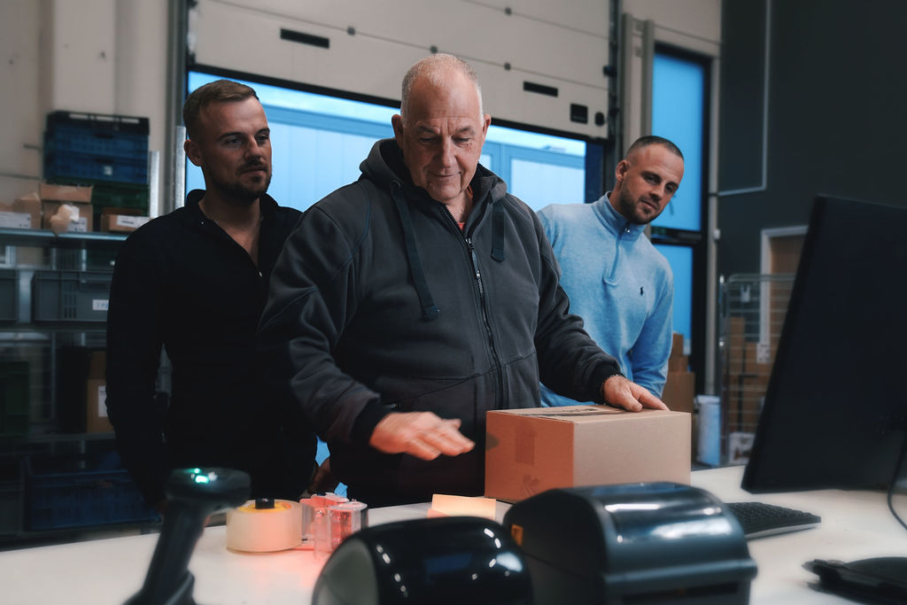 Jordy, Marco en Sven aan de werkbank van RTM Fulfilment, een pakket wordt klaargemaakt voor verzending